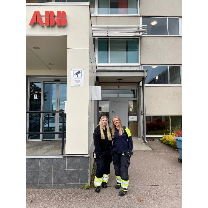 Tv&aring; kvinnor st&aring;r framf&ouml;r en byggnad d&auml;r det st&aring;r ABB p&aring; en pelare. Den ena kvinnan &auml;r handledare &aring;t den andra genom Teknikspr&aring;nget. 