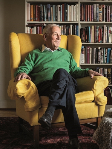 Hans i gul fåtölj med en hund