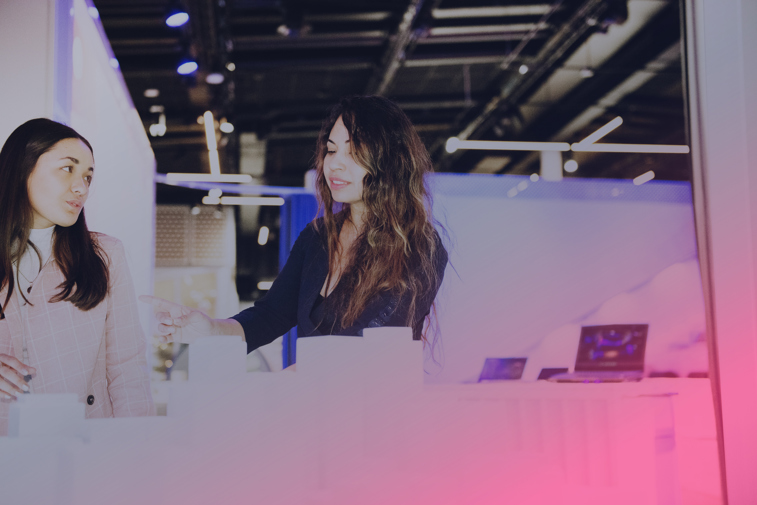 Två kvinnor går ned för en trappa, de är djupt inne i en diskussion. Modern interiör.