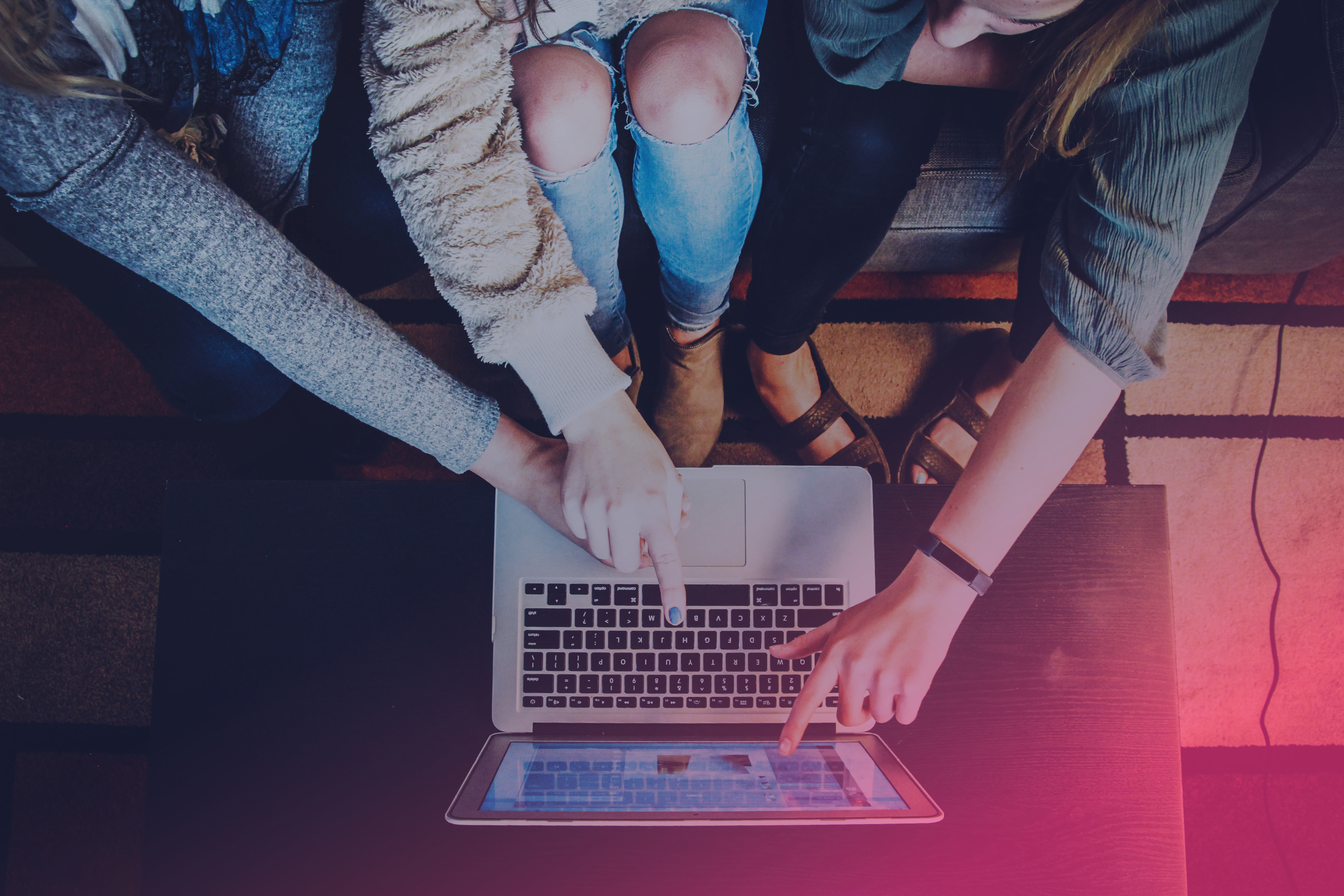 Three people point at a laptop screen.