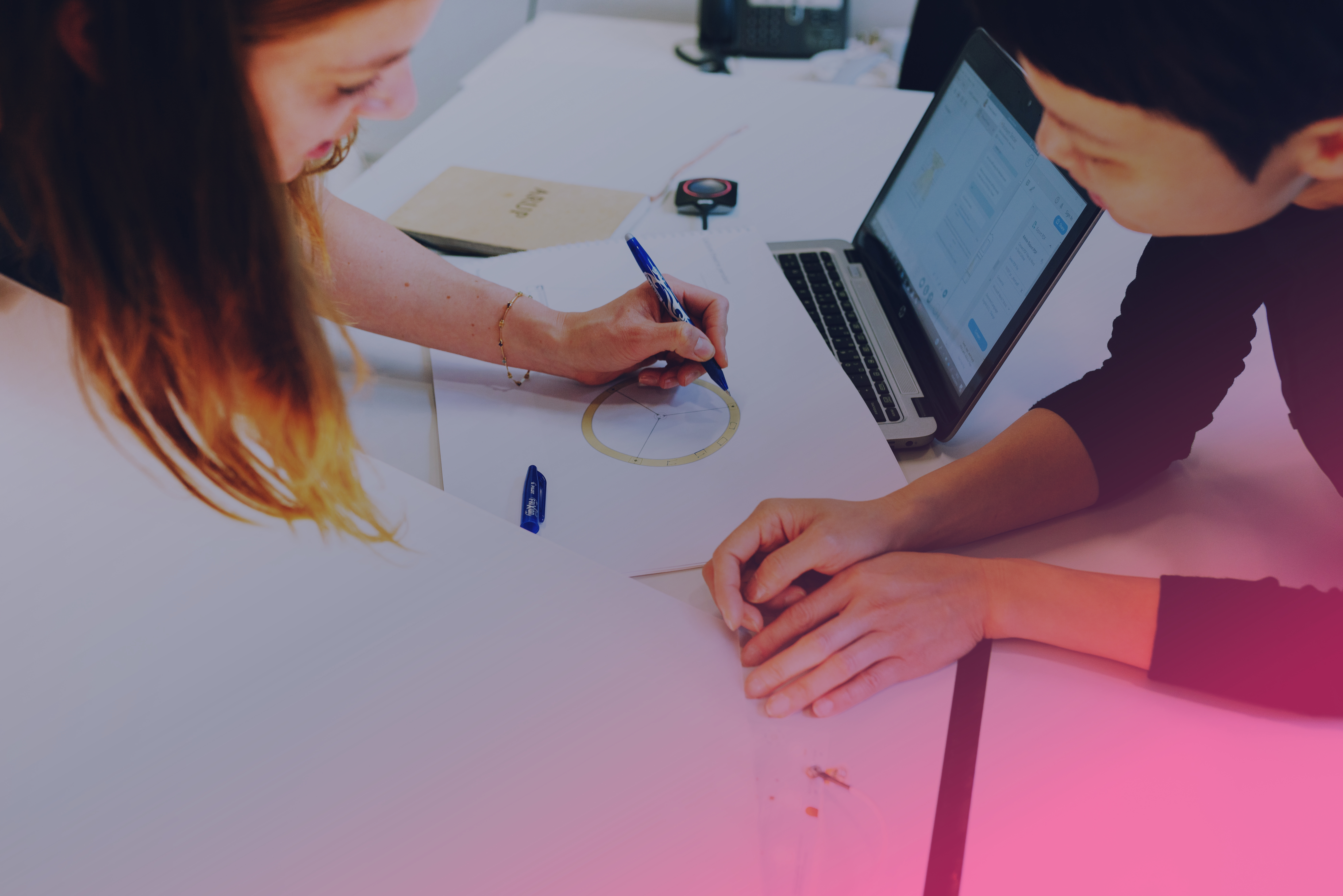 Woman receives supervision at computer by male supervisor. With pink filter.