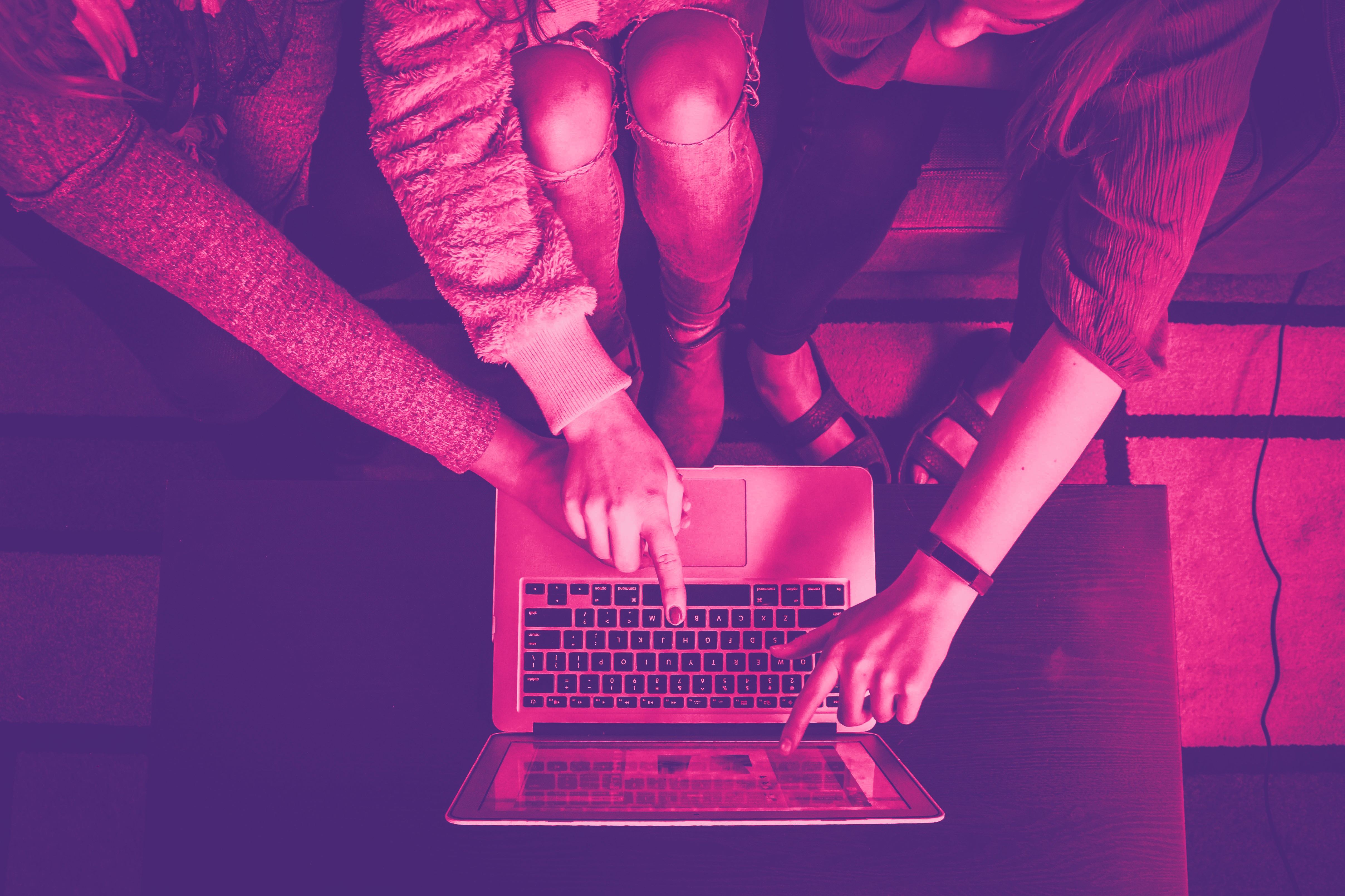 Three people point to a laptop screen