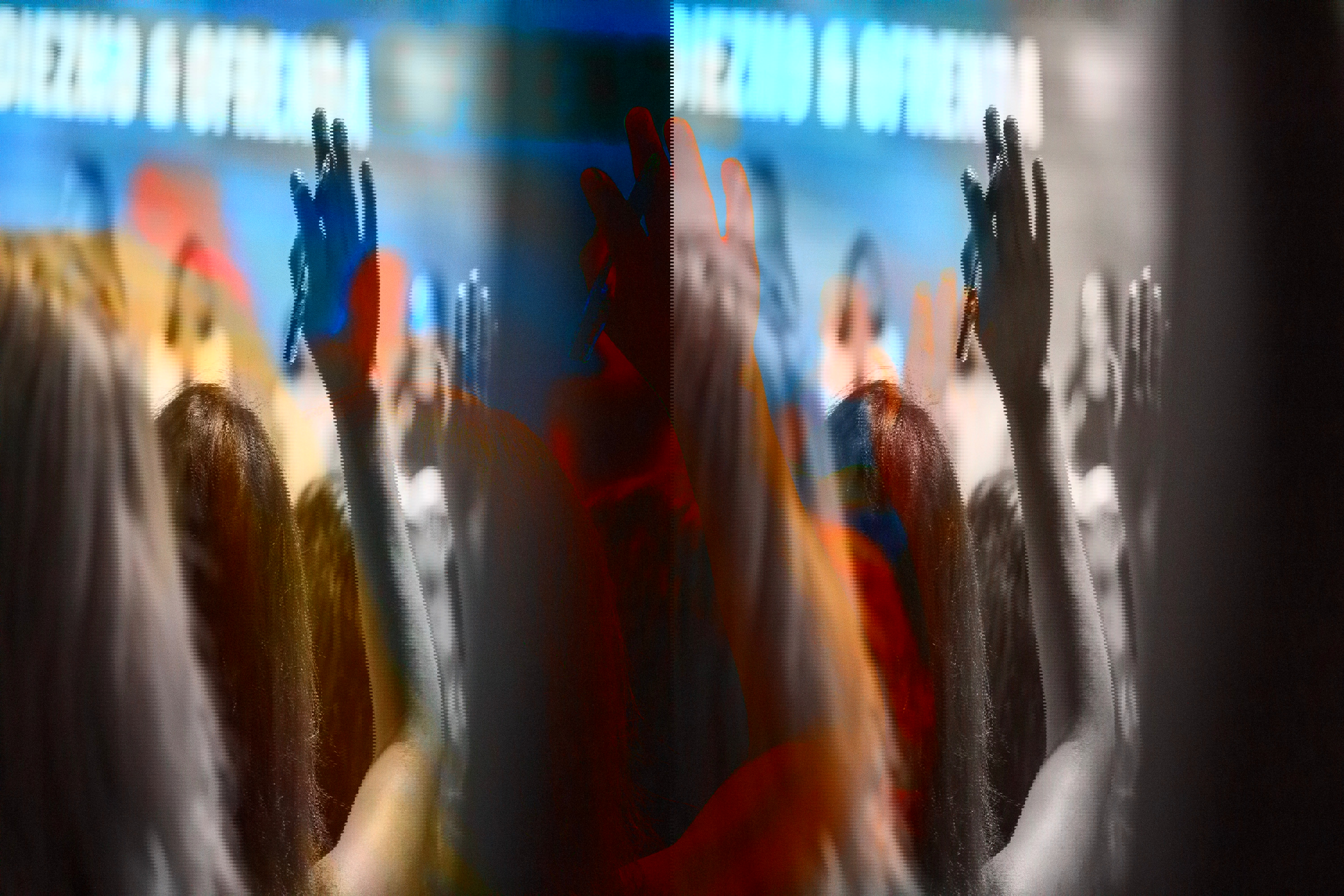 En person räcker upp handen på ett seminarium. Med rosa filter