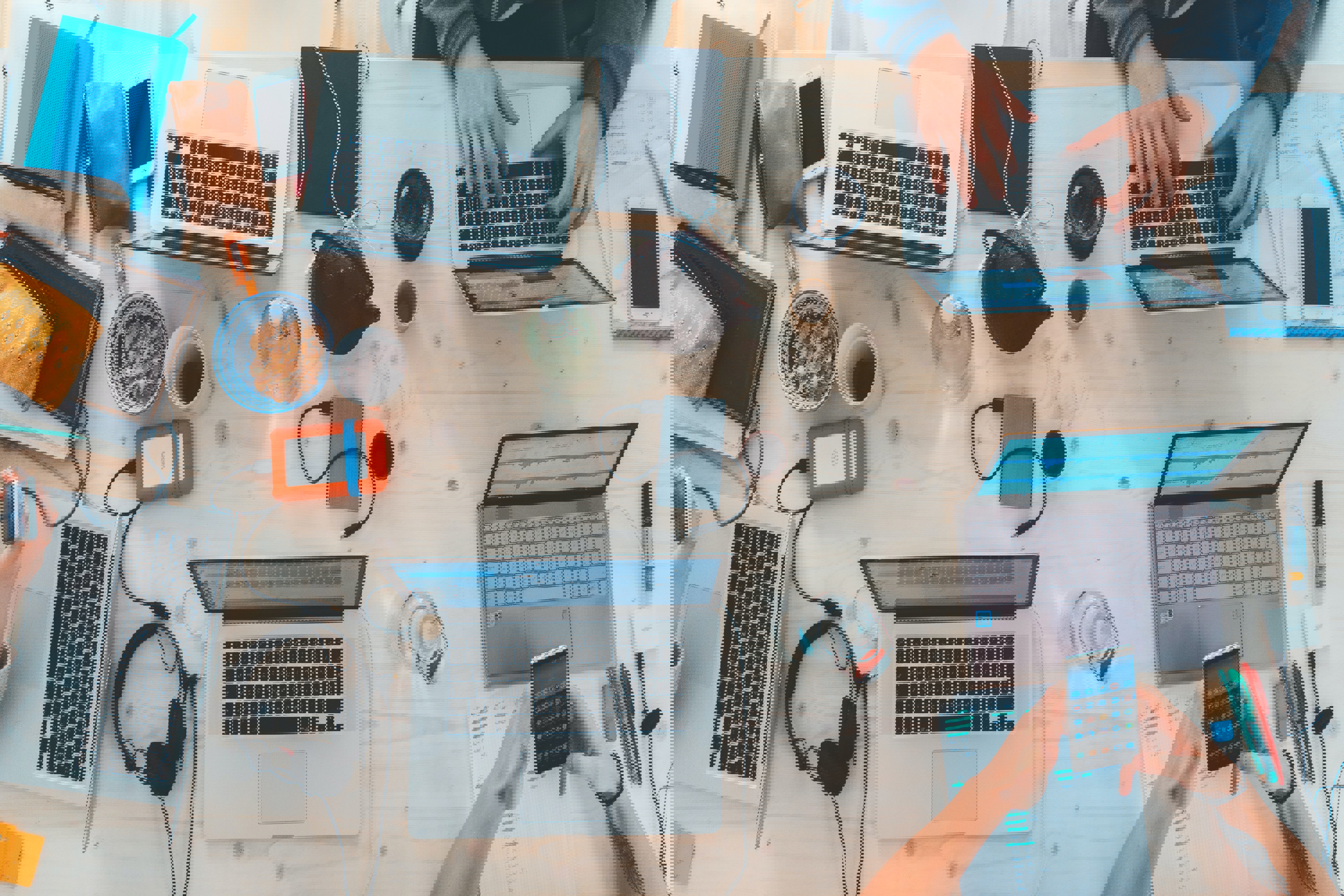 A desk filled with computers, cables, and people working. Gives a wonderfully messy feeling