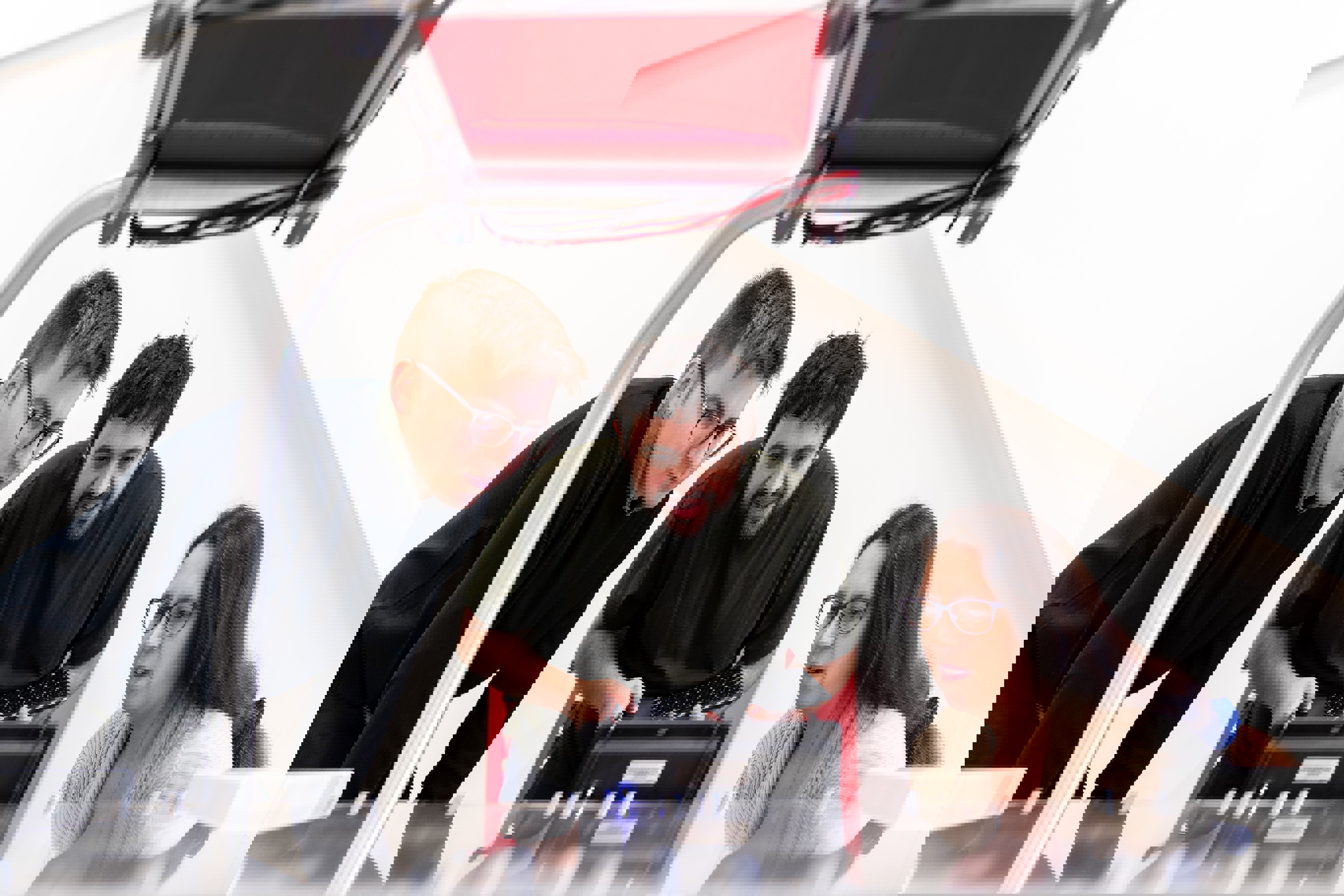 Three people look at a small machine.