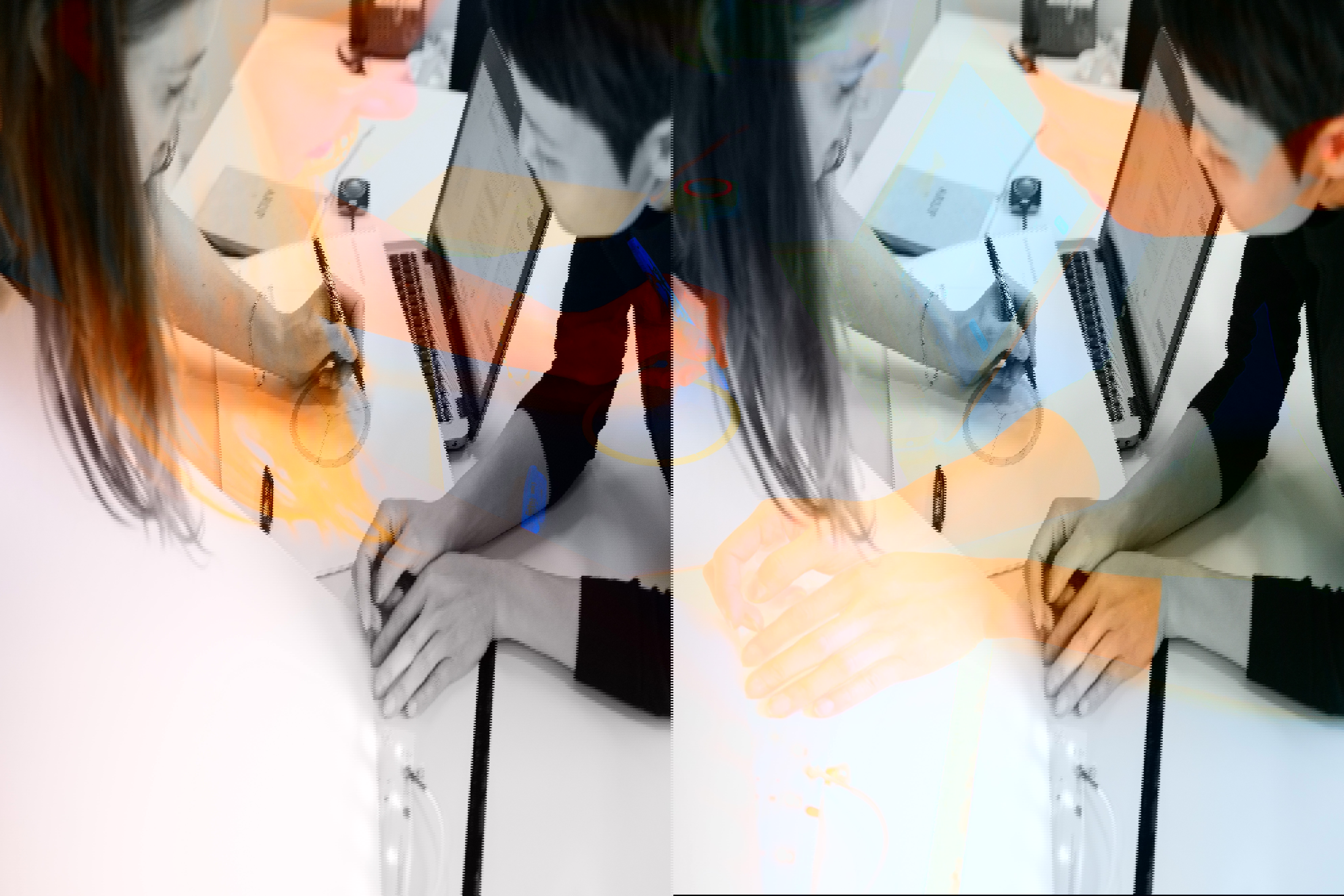 Tre personer som arbetar över en arbetsbänk, en av dem tycks måla på en ritning